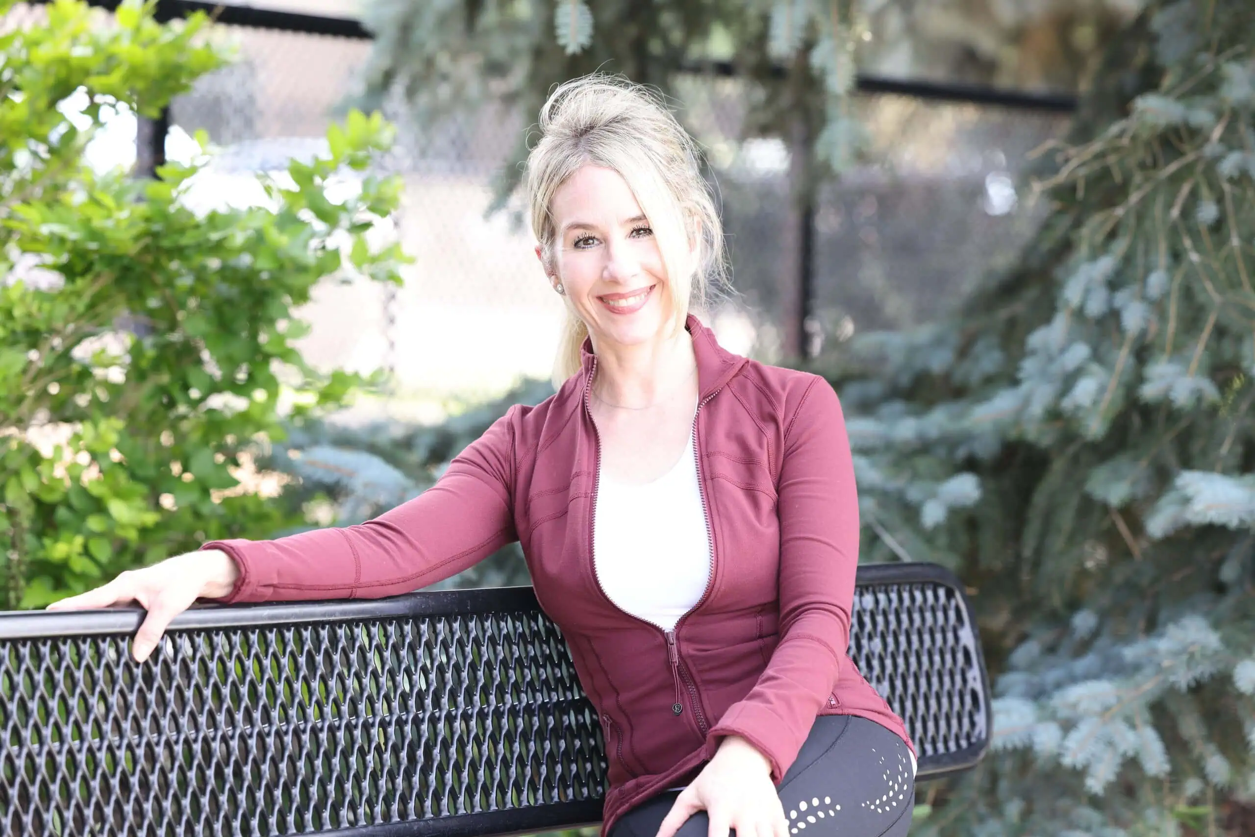 Sheree smiling sitting on a bench outside