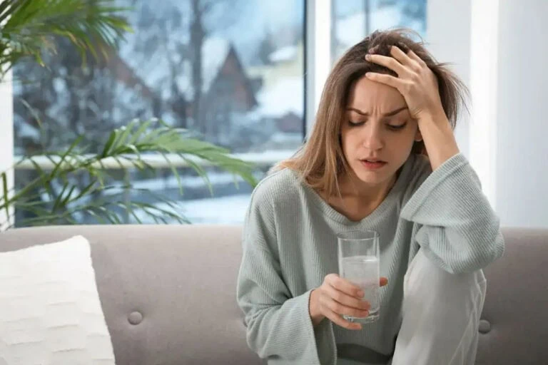 Woman with a headache sitting on the couch