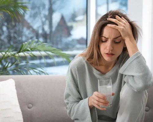 Woman with a headache sitting on the couch