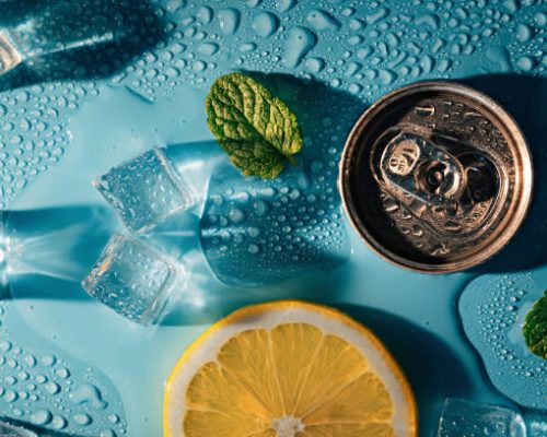 Creative summer composition with lemon slice, mint leaves, can of soda and ice cubes. Top down minimal lemonade drink concept.