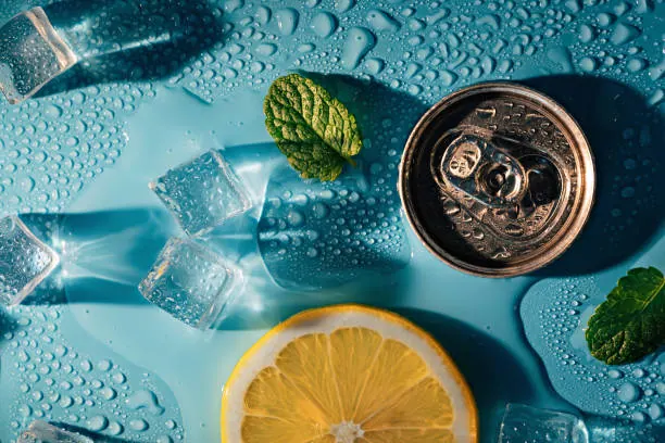 Creative summer composition with lemon slice, mint leaves, can of soda and ice cubes. Top down minimal lemonade drink concept.