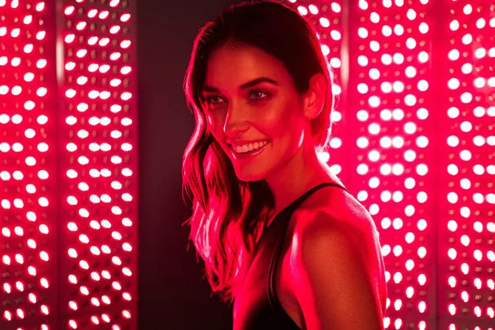 A woman smiling while receiving red light therapy.