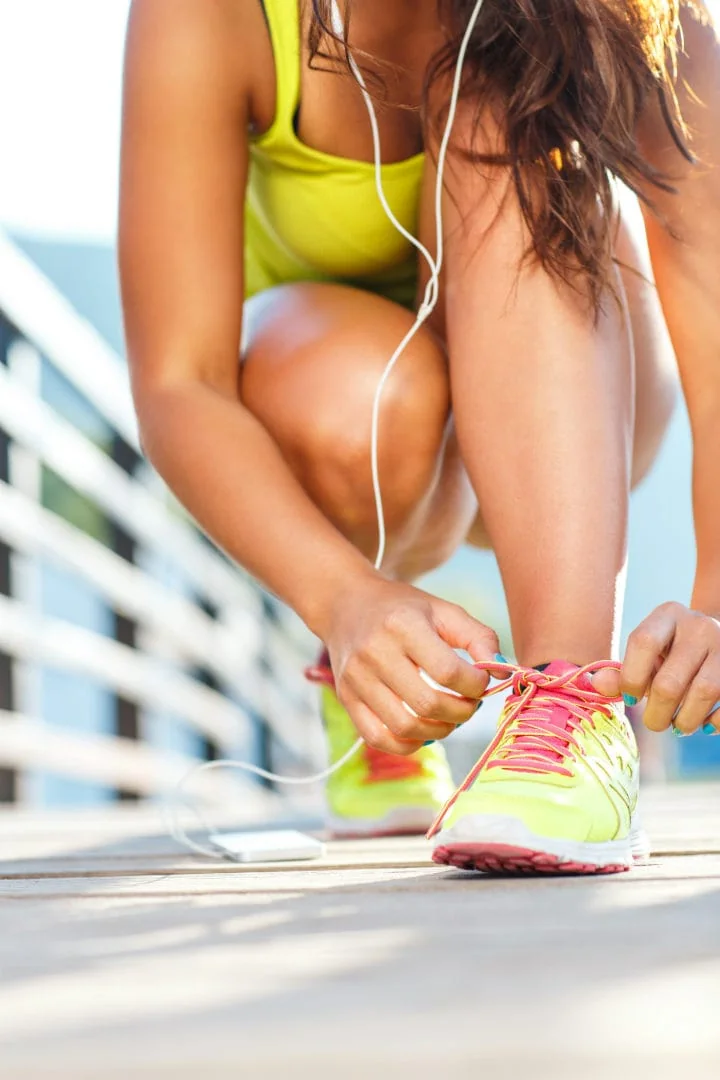 A woman lacing up her running shoes.